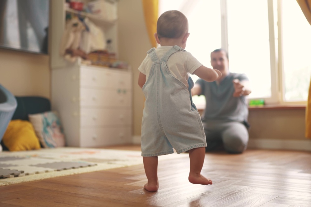 A toddler walking towards a parent.