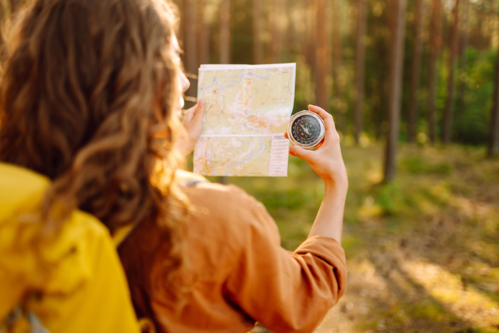 A young woman hiking and using a compass.