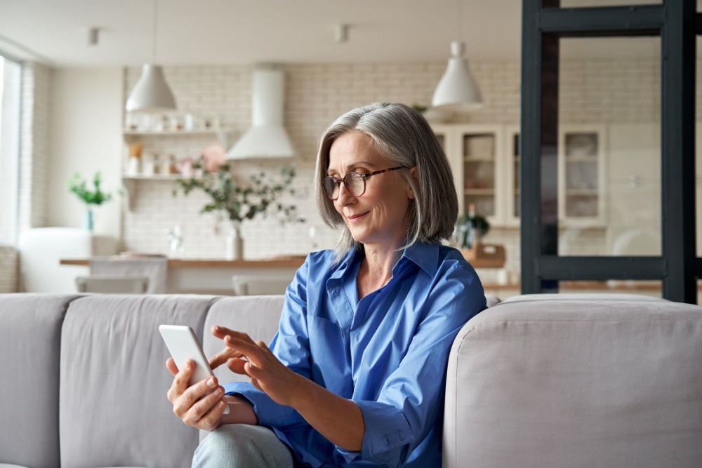 A woman in her 60s checking something on her mobile phone.