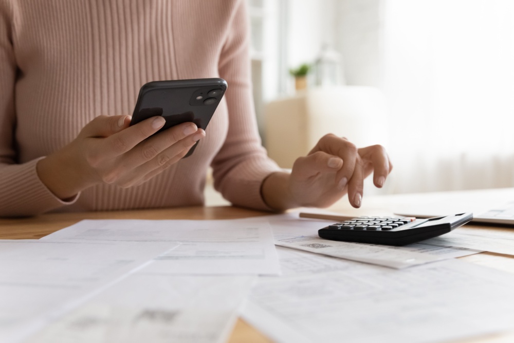 A woman using a phone and calculator.