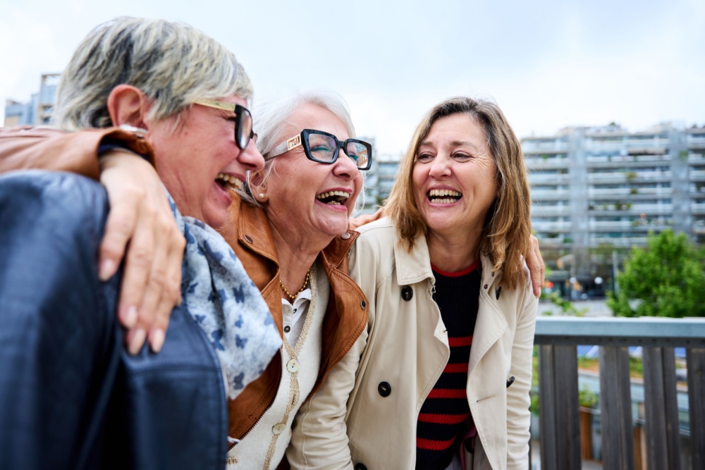 Three women with the around each other laughing.