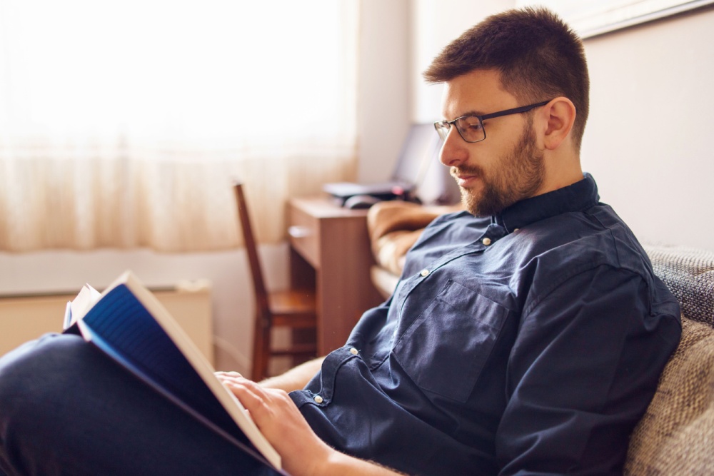 A man reading a book in his home.